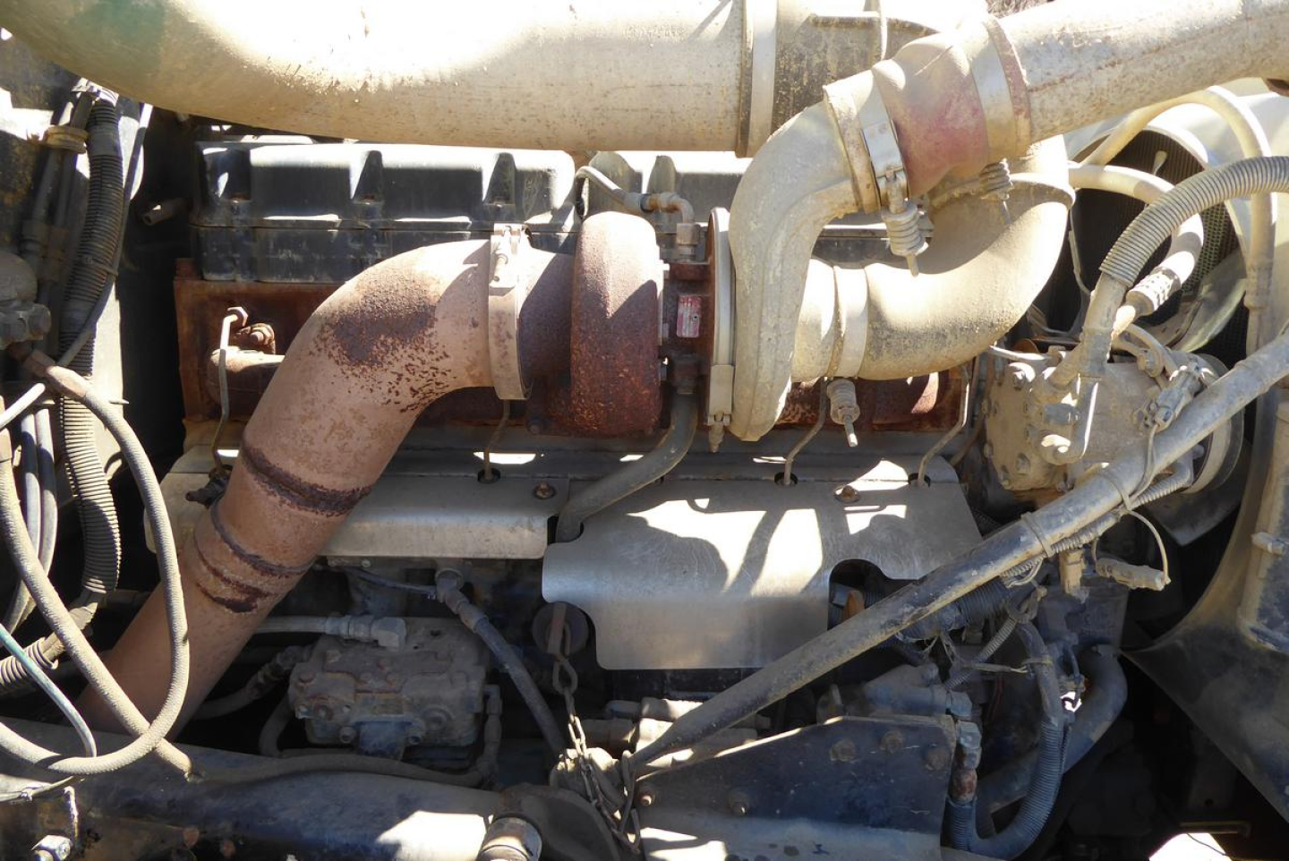 Engine bay showing exhaust manifold, turbocharger, hoses, and diesel engine components.