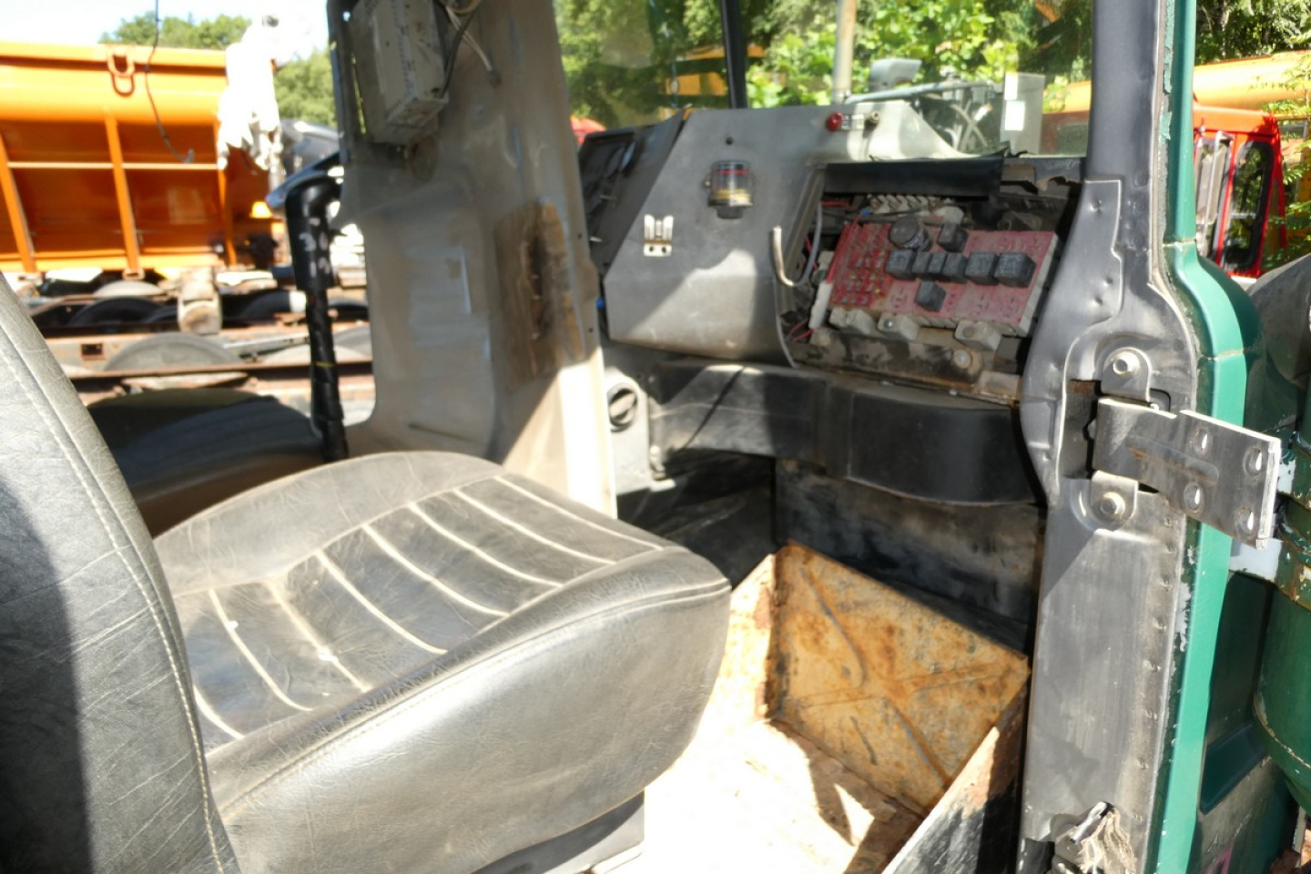 Cab and chassis interior of 1999 Mack RD688S showing dash with exposed wiring and a single seat, worn flooring, and open access to engine area.
