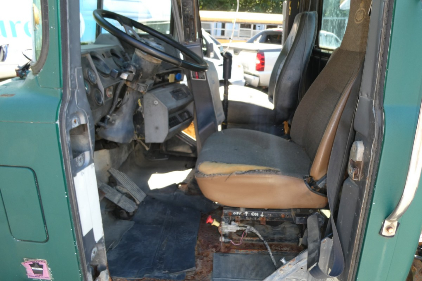 Cab and chassis truck interior showing seat and steering wheel of a green Mack RD688S with visible wear and exposed floor area.