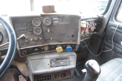 Cab and chassis dash panel with gauges and switches in a 1999 Mack RD688S truck interior showing faded instrument cluster and control knobs.