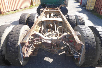 Chassis frame and tandem rear axle of a 1999 Mack RD688S cab and chassis showing rusted frame and multiple drive axles.