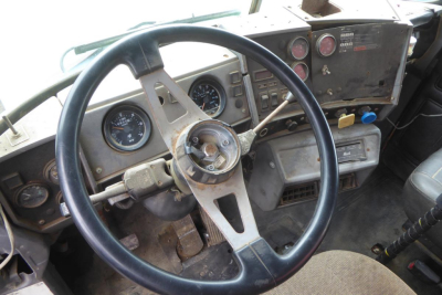 Mack RD688S dash and steering wheel showing gauges and old instrument cluster. Steering wheel with three spokes, circular speedometer, and control panel with switches.