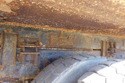 Rear undercarriage showing rusted frame rails and spare tire mounted with bolts and springs on a Mack RD688S chassis.