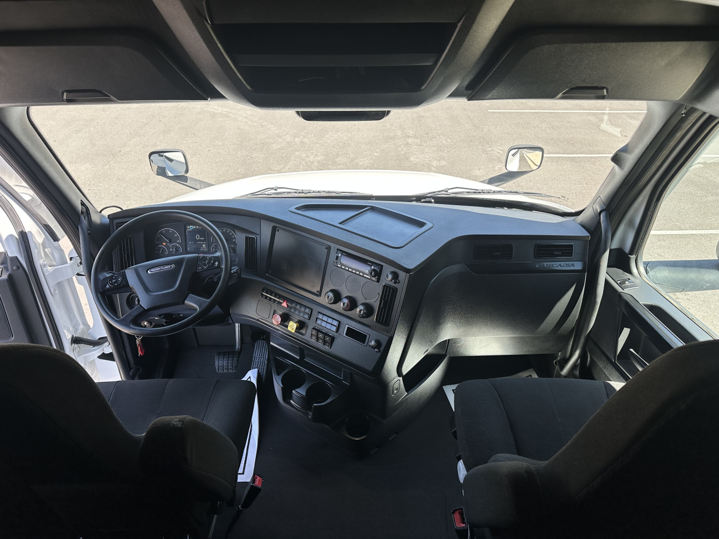 Cab view of a 2023 Freightliner Cascadia 126 truck interior showing steering wheel, dashboard, and driver and passenger seats.
