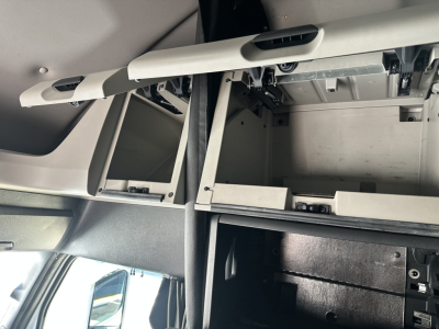 Cab interior under-dash storage with open compartments in a Freightliner Cascadia cab.