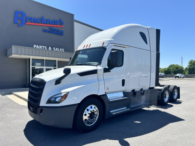 Front right-side view of a white 2023 Freightliner Cascadia 126 semi-truck in a dealership lot, exterior chrome mirrors, large sleeper cab, aerodynamic hood, 6-wheel configuration visible.