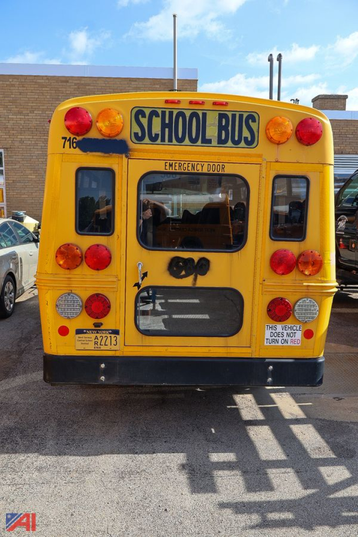 Rear view of a yellow Chevrolet Express school bus with 'SCHOOL BUS' sign, emergency door, and multiple red/amber lights.