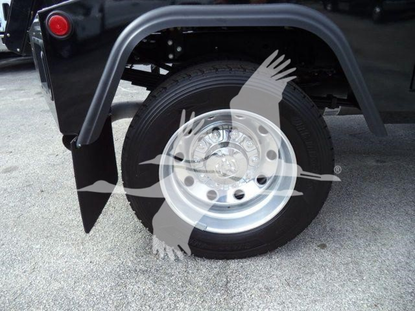 Truck wheel and fender area showing large single rear wheel, metallic wheel with hub, black tire, and curved gray fender flare; part of a Ram 4500 chassis in a dealership lot.