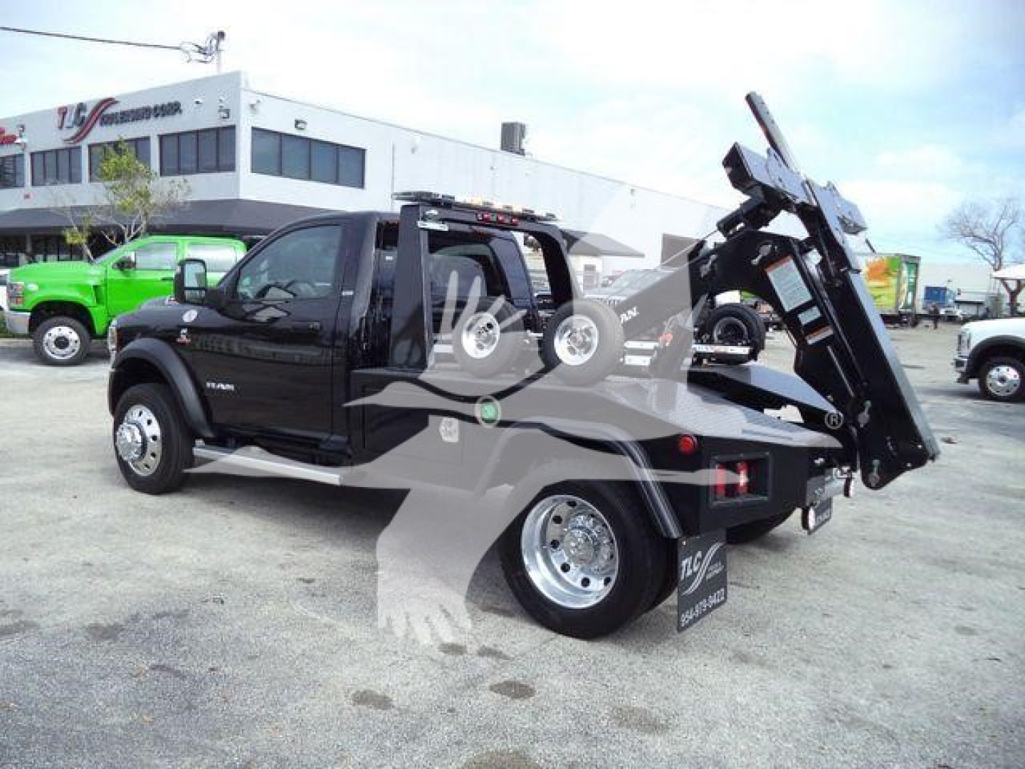 2024 Ram 4500 SLT tow truck body with hydraulic bed and winch, black crew cab, side view showing heavy-duty towing equipment and wheel rims.