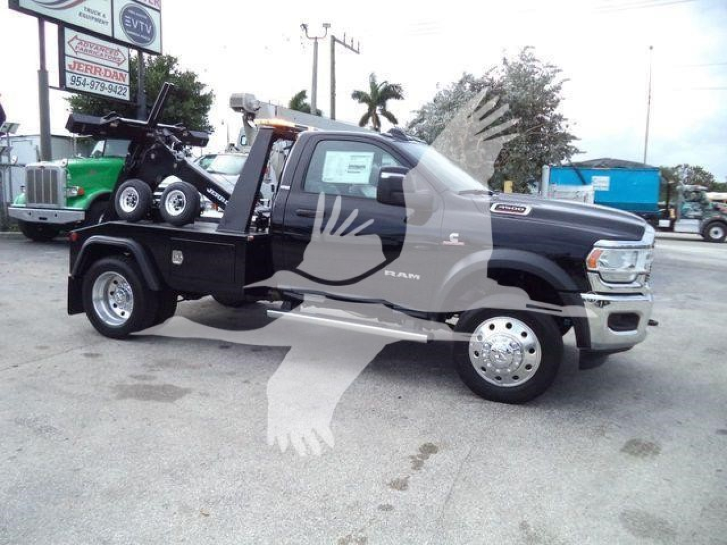 Ram 4500 SLT tow truck with a flatbed and winch, black cab, dual rear wheels, displayed in a dealership lot.