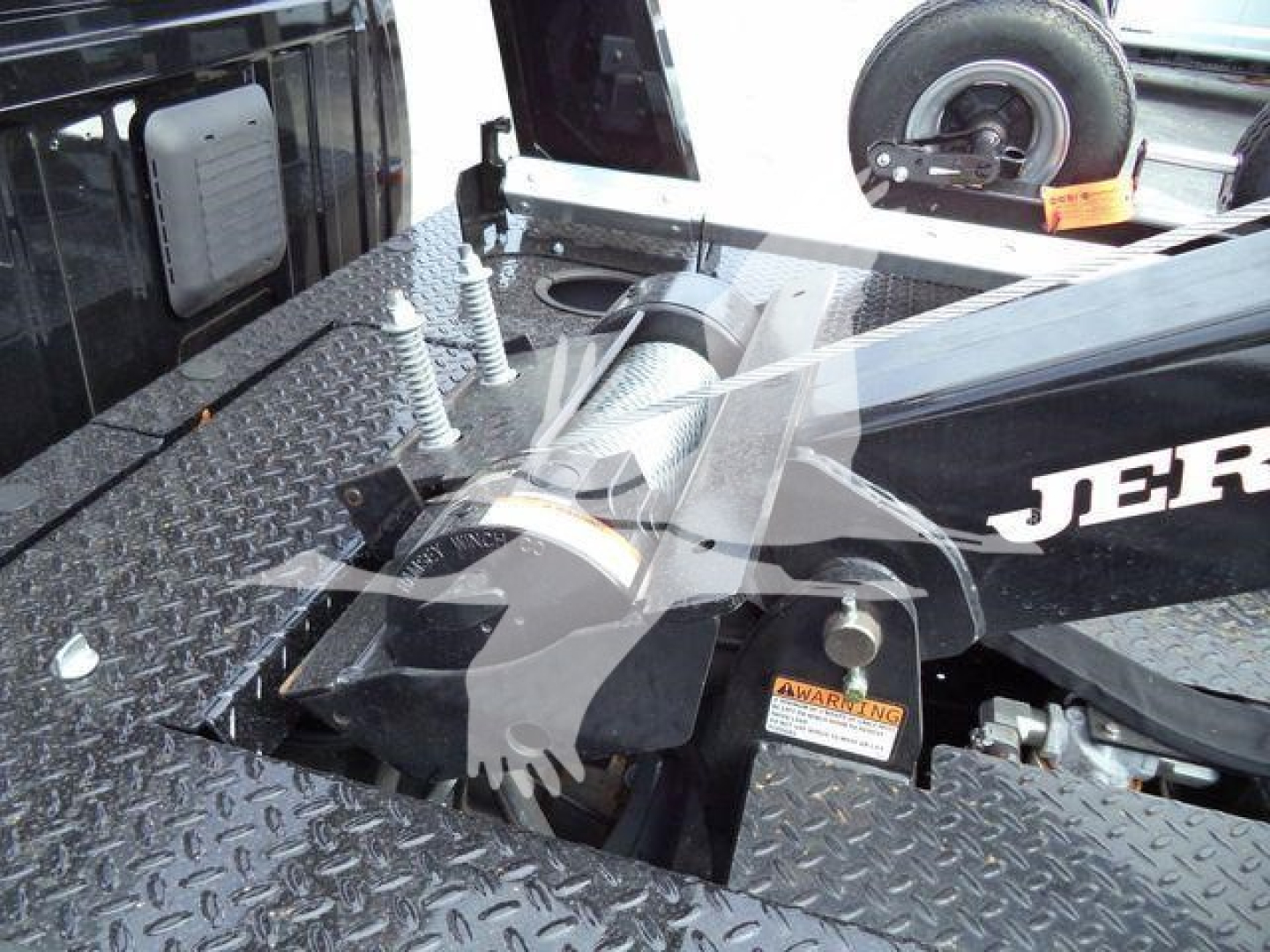 Ram 4500 SLT winch truck bed showing winch area and diamond plate platform with tire on the side and warning label visible.