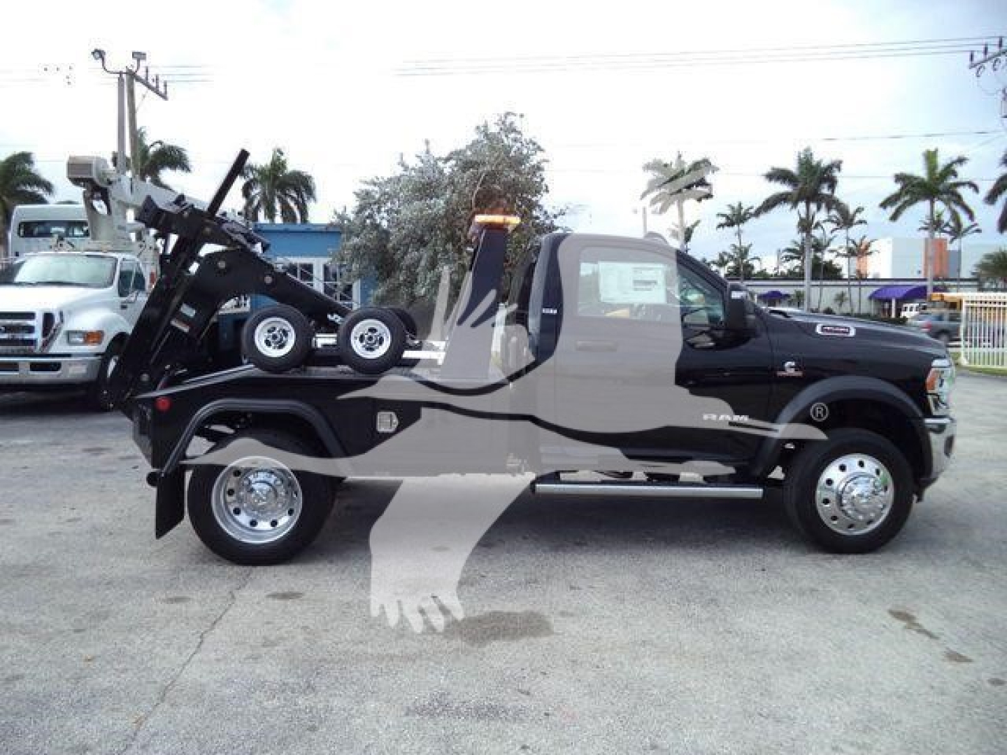 Ram 4500 tow truck side view showing winch rack and mechanical arm, black extended cab with chrome wheels