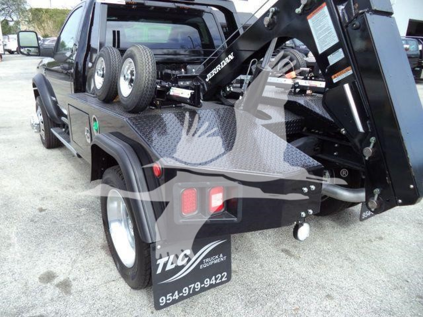 Ram 4500 dump bed with tow hitch, spare tires, and hydraulic winch crane in rear view showing metal diamond plate bed