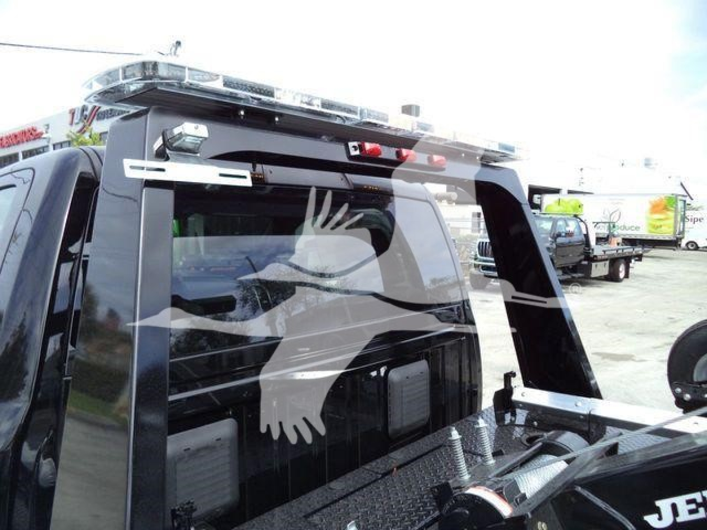 Truck bed area with a large winch on the back, rear window with a silhouette decal of an eagle in flight, roof light bar, and metal diamond plate toolbox.