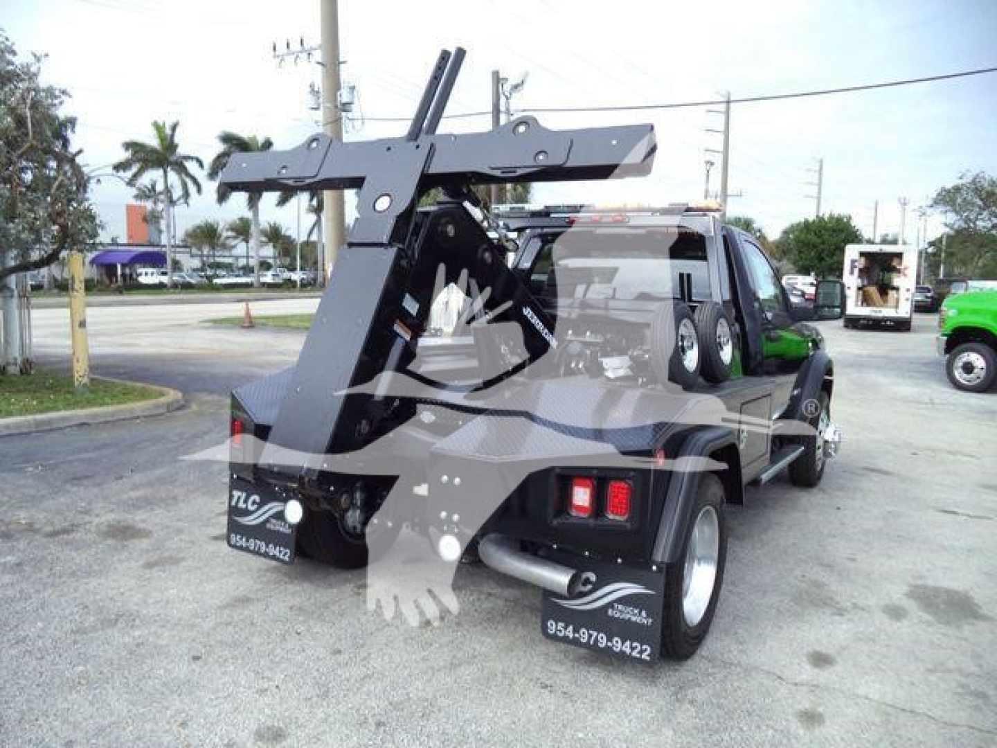 Ram 4500 tow truck with a large overhead winch mount and crane, black/dark gray tow equipment, dual rear tires, rear bumper with light clusters, dealership decals.