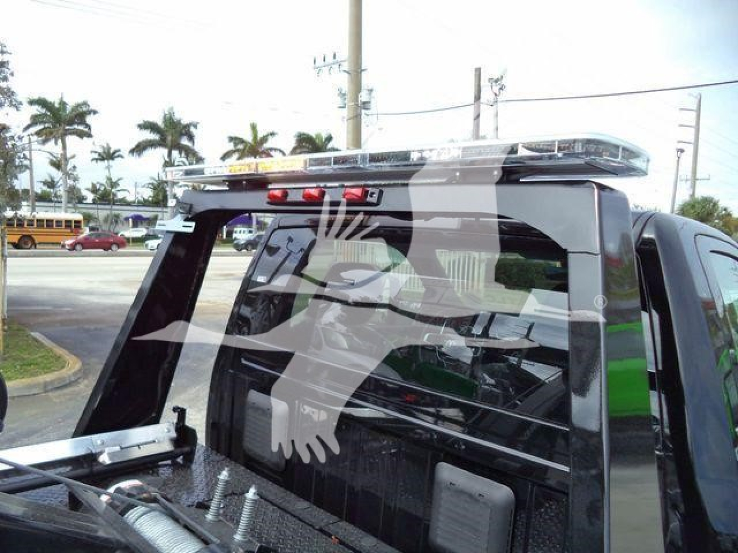 Truck bed with winch equipment on a 2024 Ram 4500 SLT, rear window guard, roof-mounted beacon bar visible.
