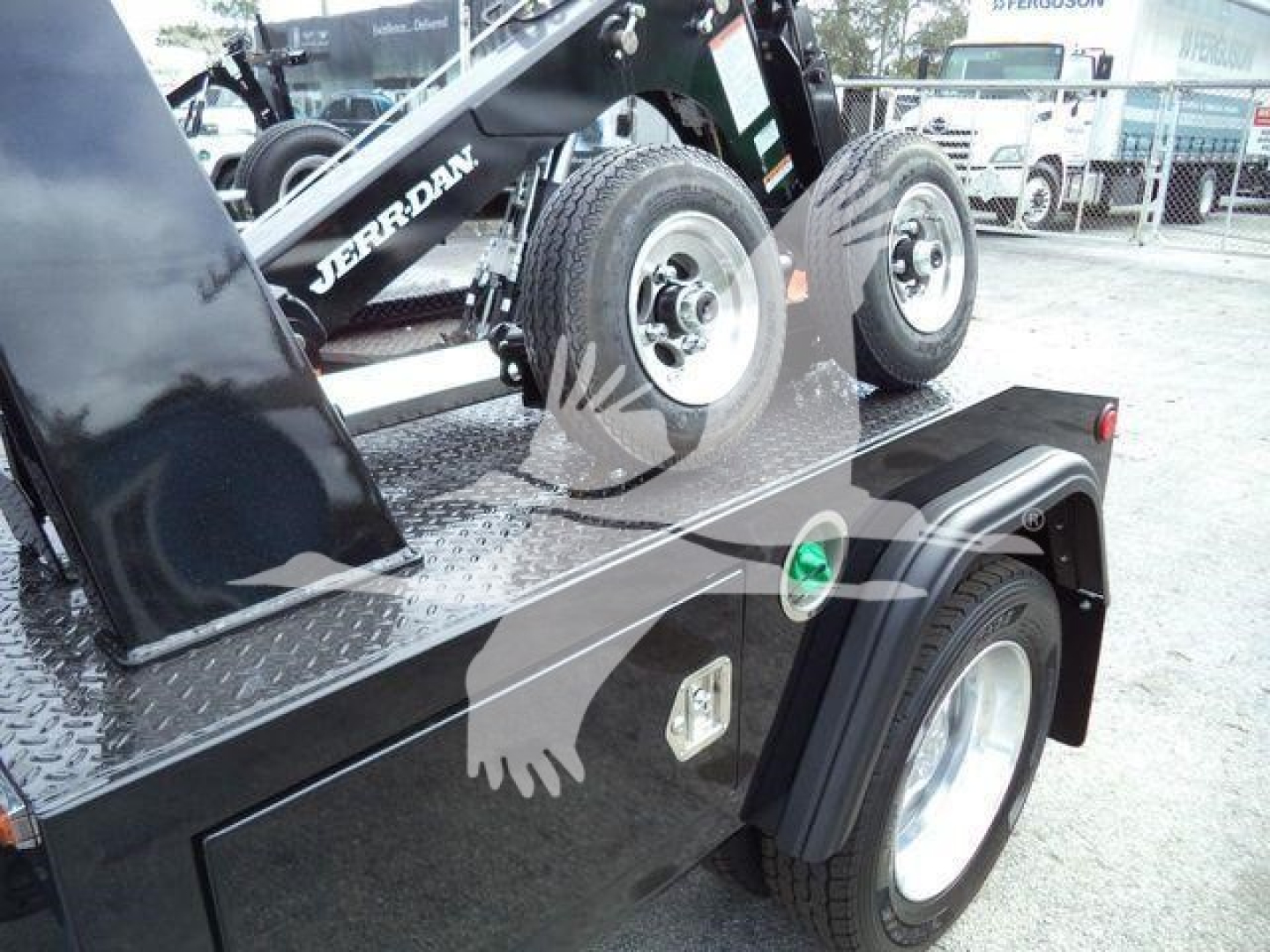 Ram truck winch setup on flatbed with dual rear tires; visible labels: 'JERRDAN' on crane arm and green circular indicator on fender; diamond plate deck; wheel and fender details.