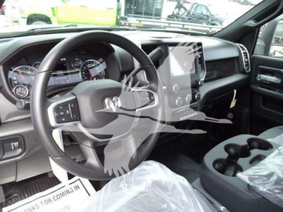 Ram 4500 interior view showing steering wheel, dashboard, and center touchscreen; plastic seat coverings indicate new condition; visible dials and gear shifter.