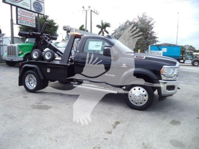 Ram 4500 SLT tow truck with a flatbed and winch, black cab, dual rear wheels, displayed in a dealership lot.