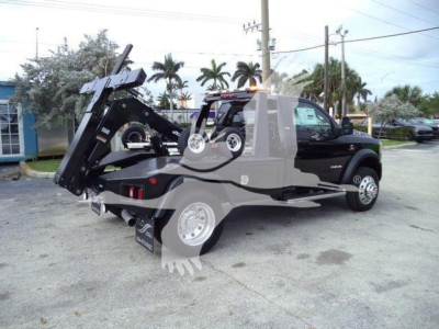 Ram 4500 SLT tow truck with integrated winch setup and hydraulic rollback bed in a dealership lot.