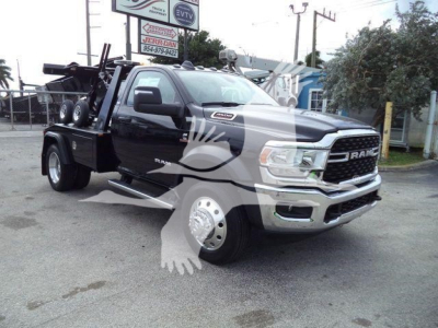 Ram 4500 pickup truck with winch equipment in bed, black exterior, showing RAM grille and large chrome bumper; front wheel close-up; no visible labels readable