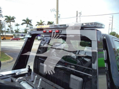 Truck bed with winch equipment on a 2024 Ram 4500 SLT, rear window guard, roof-mounted beacon bar visible.