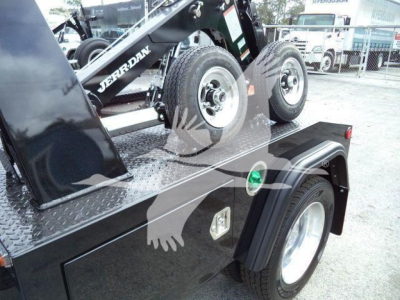 Ram truck winch setup on flatbed with dual rear tires; visible labels: 'JERRDAN' on crane arm and green circular indicator on fender; diamond plate deck; wheel and fender details.