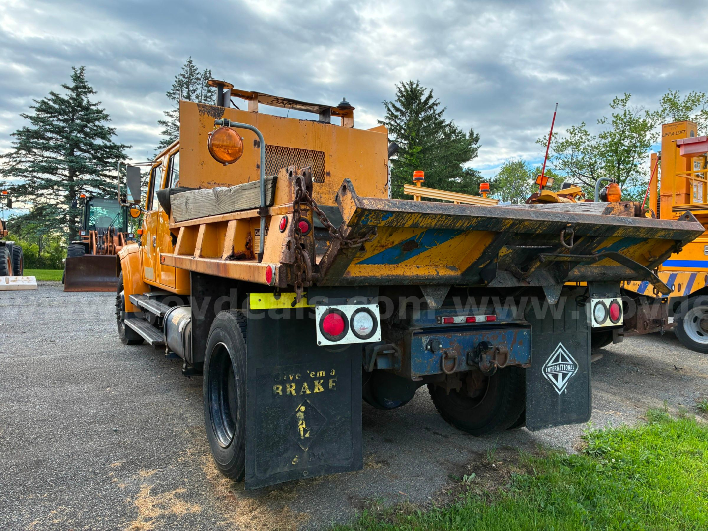 Dump truck bed of a used 2002 International 4700 in a lot, rear view with yellow paint and black mud flaps.