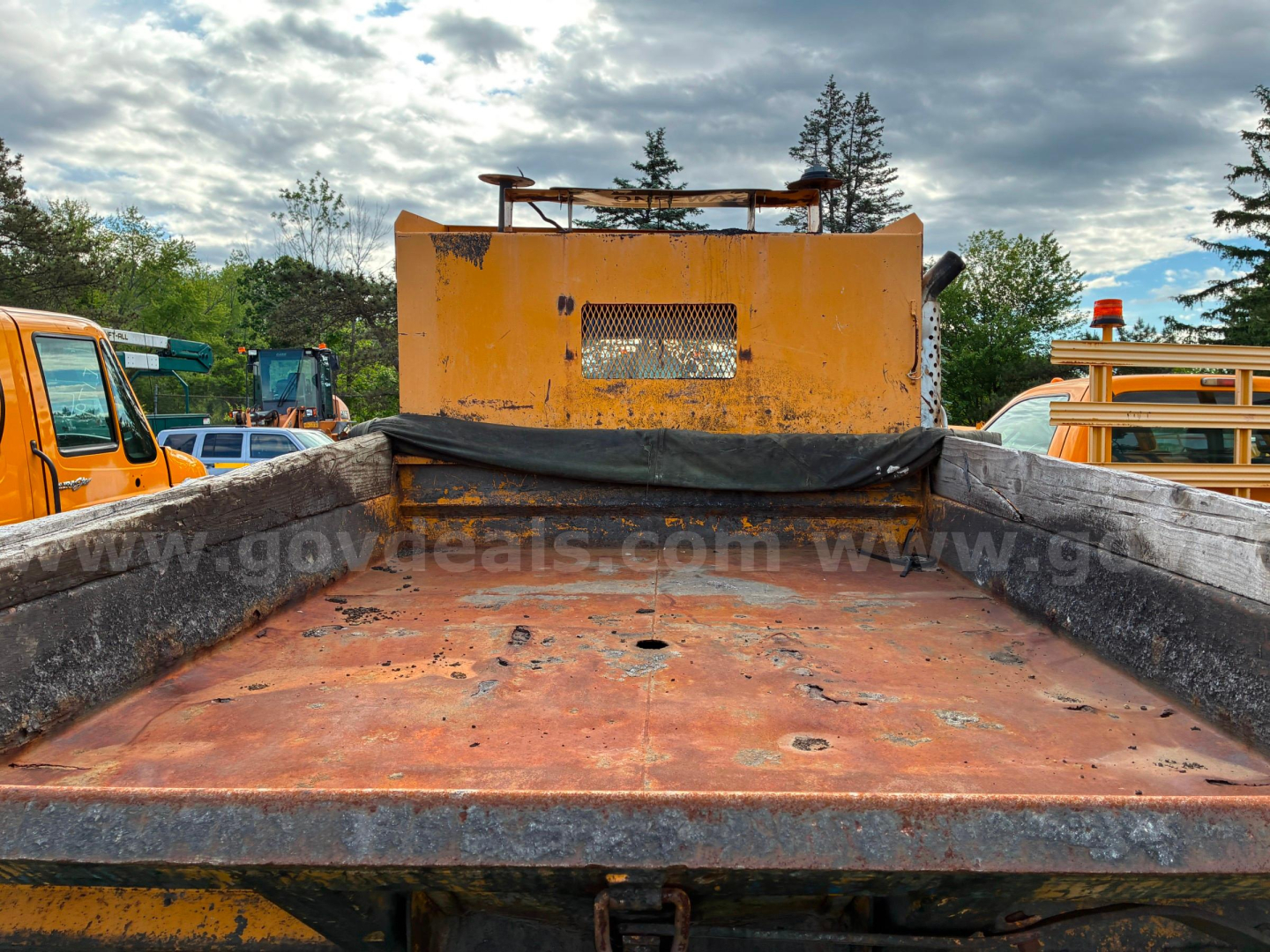 Dump bed of a 2002 International 4700 dump truck showing rusted metal bed and yellow cab in background.