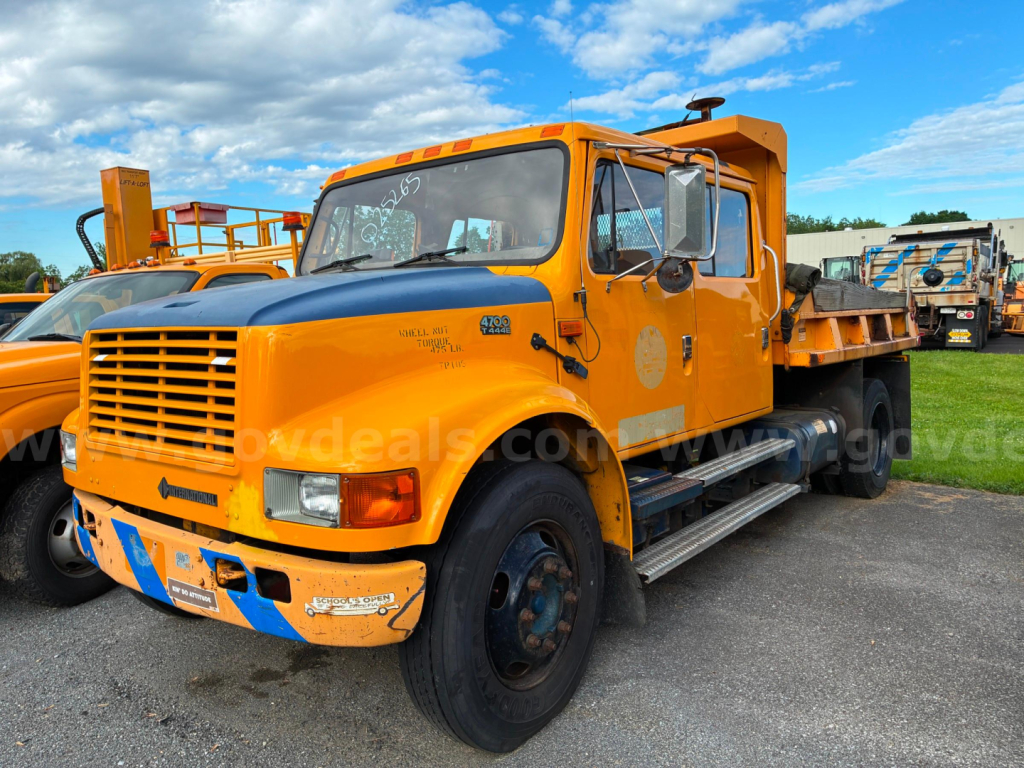 Yellow 2002 International 4700 dump truck side view showing front grille, cab with steps, and dump bed.