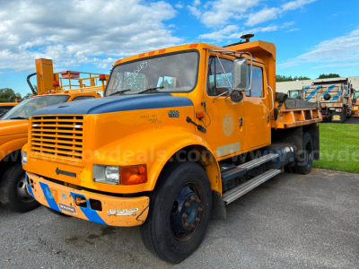Yellow 2002 International 4700 dump truck side view showing front grille, cab with steps, and dump bed.
