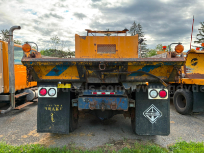 Dump truck rear showing International 4700 ballast and hydraulic bed with mud flaps and taillights.