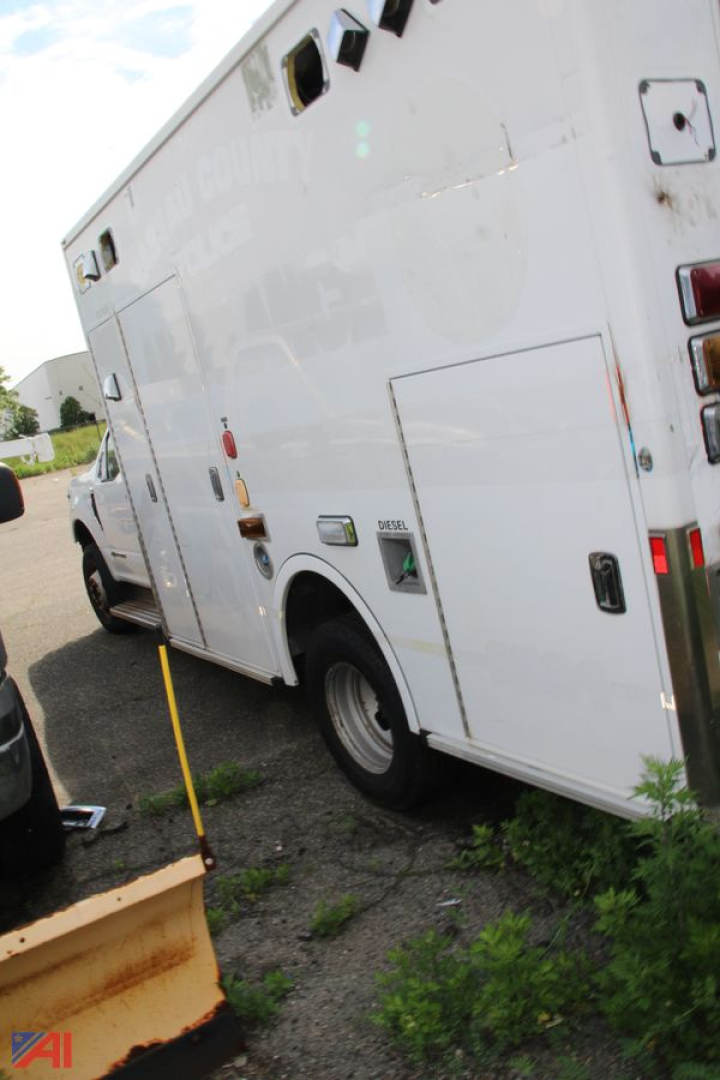 Ambulance side rear view showing cargo doors and wheel well with small decals and lights.