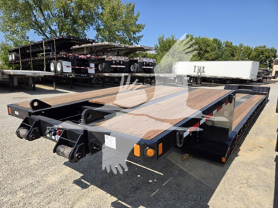 Flatbed trailer with dual drop deck showing two coupling hitches and tail lights, Fontaine Renegade X20 model text not visible; wooden deck surface and black metal frame.