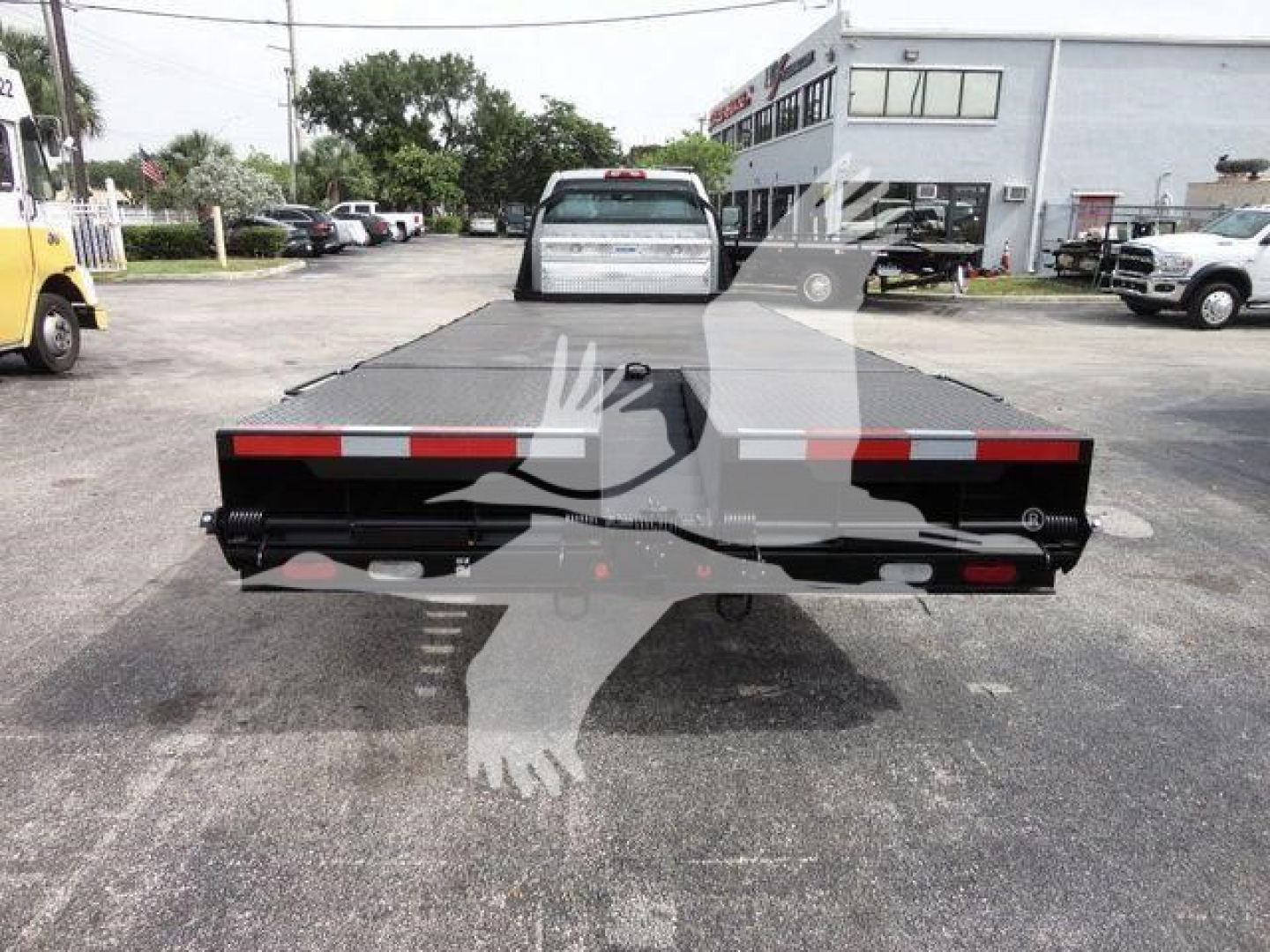 Flatbed truck bed rear view of a 2023 Chevrolet Silverado 6500HD flatbed with reflective red/white striping and dual taillights.