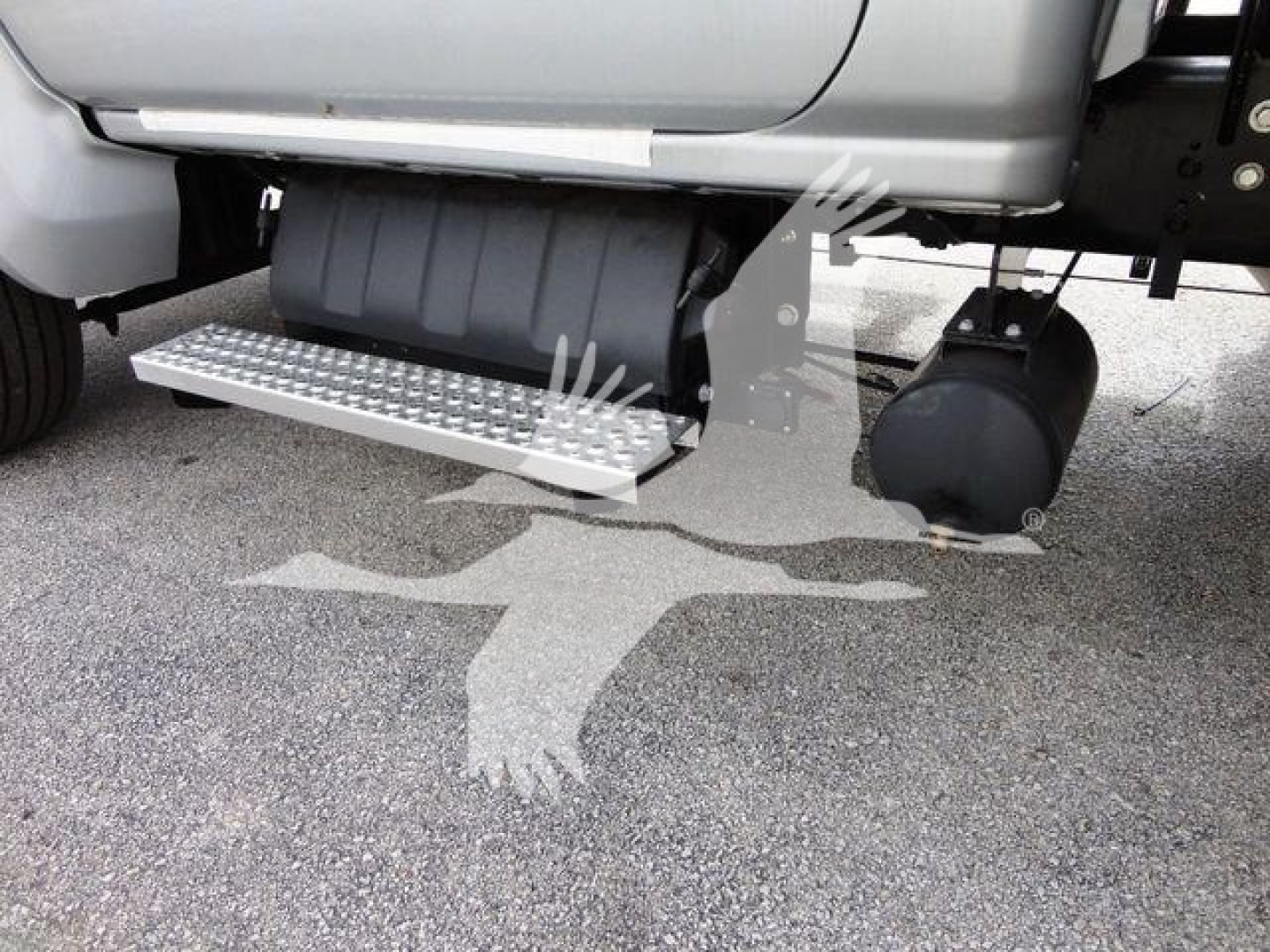 Side view of a 2023 Chevrolet Silverado 6500HD flatbed truck showing aluminum step/side step with grip surface and cylindrical fuel/air tanks under the cab.
