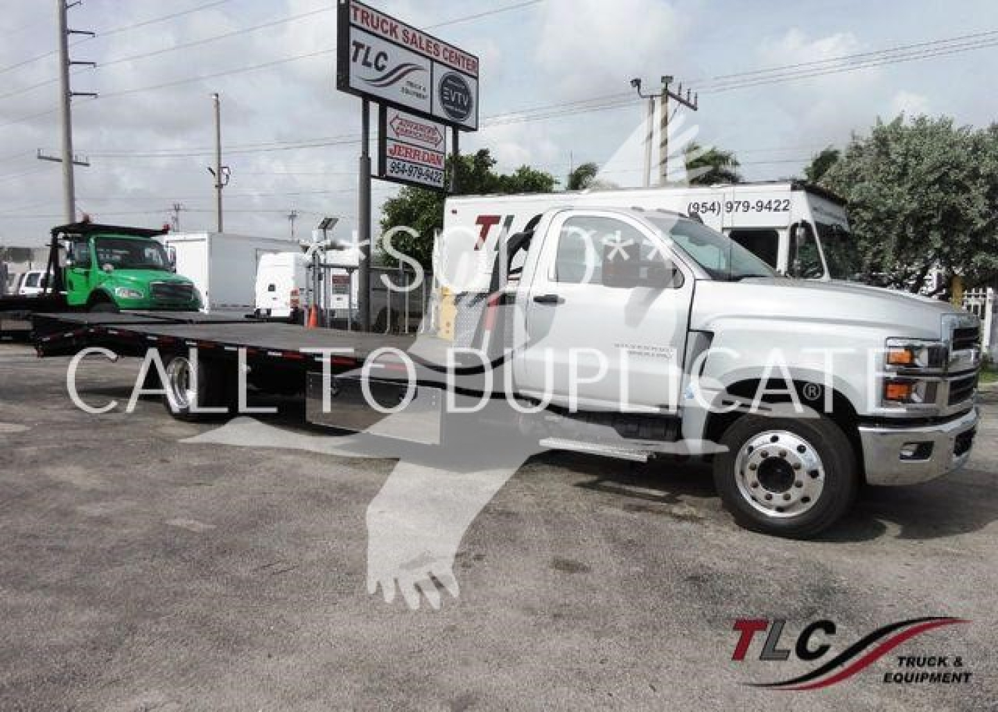 Chevrolet Silverado 6500HD flatbed truck angled view showing crew cab, front chrome bumper, and dual rear wheels with TLC logo watermark.