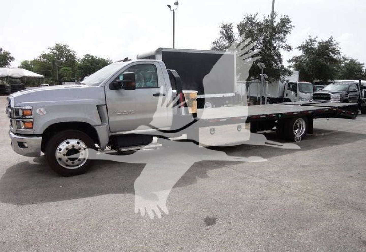 Flatbed tow truck body on a Chevrolet Silverado 6500HD chassis showing long wheelbase and dual rear wheels