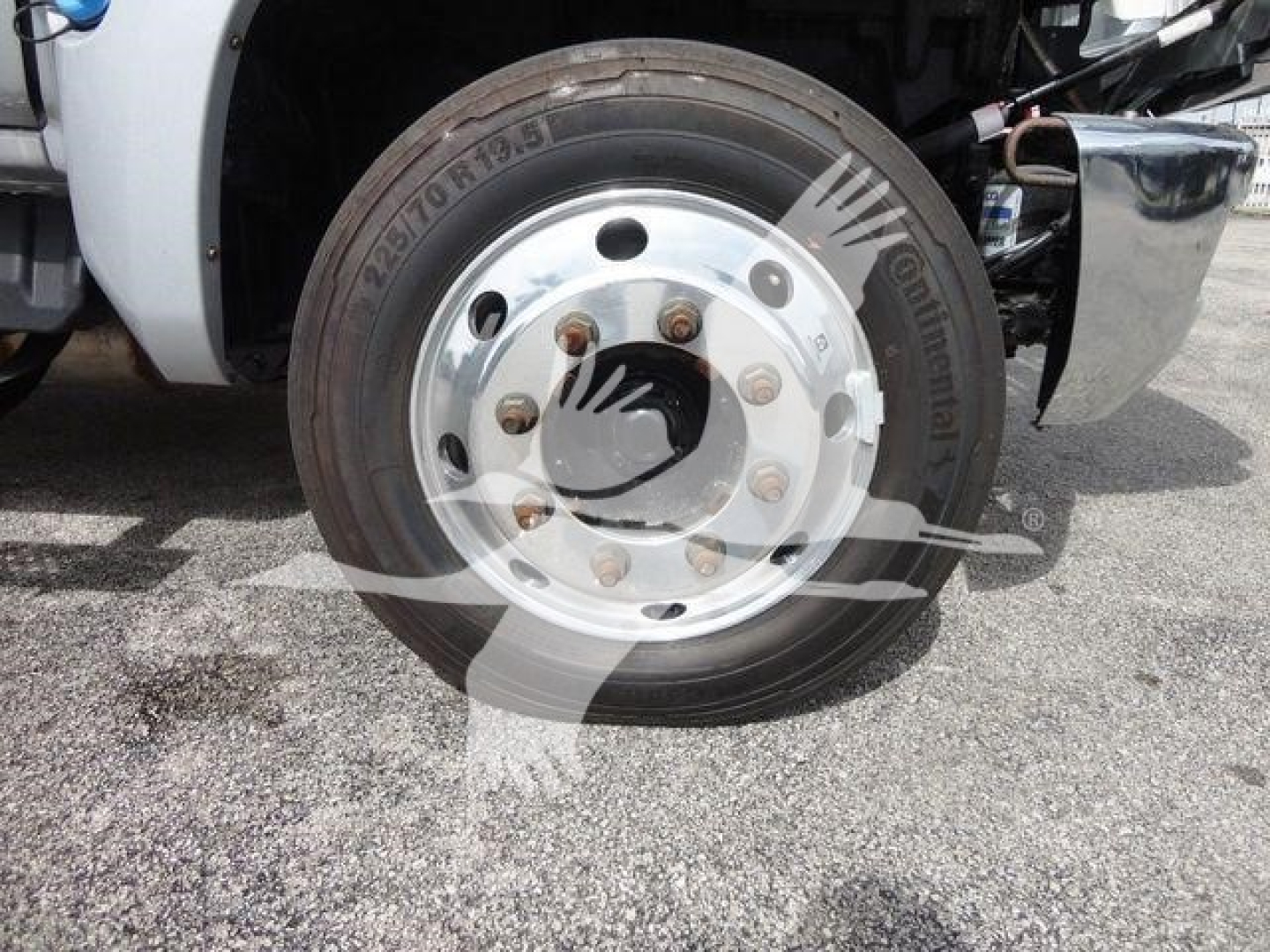 Front wheel of 2023 Chevrolet Silverado 6500HD flatbed truck showing tire with Goodyear? brand text, aluminum wheel, lug nuts, and part of the front fender.