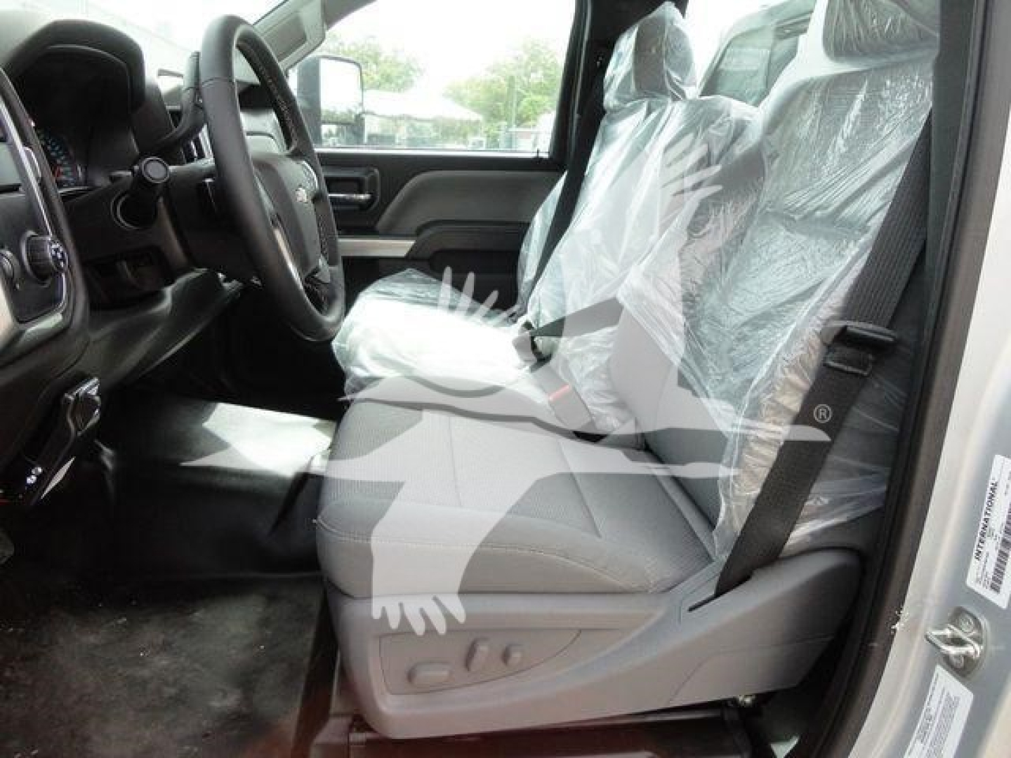 Chevrolet Silverado 6500HD flatbed truck interior showing front seats with plastic coverings and steering wheel.