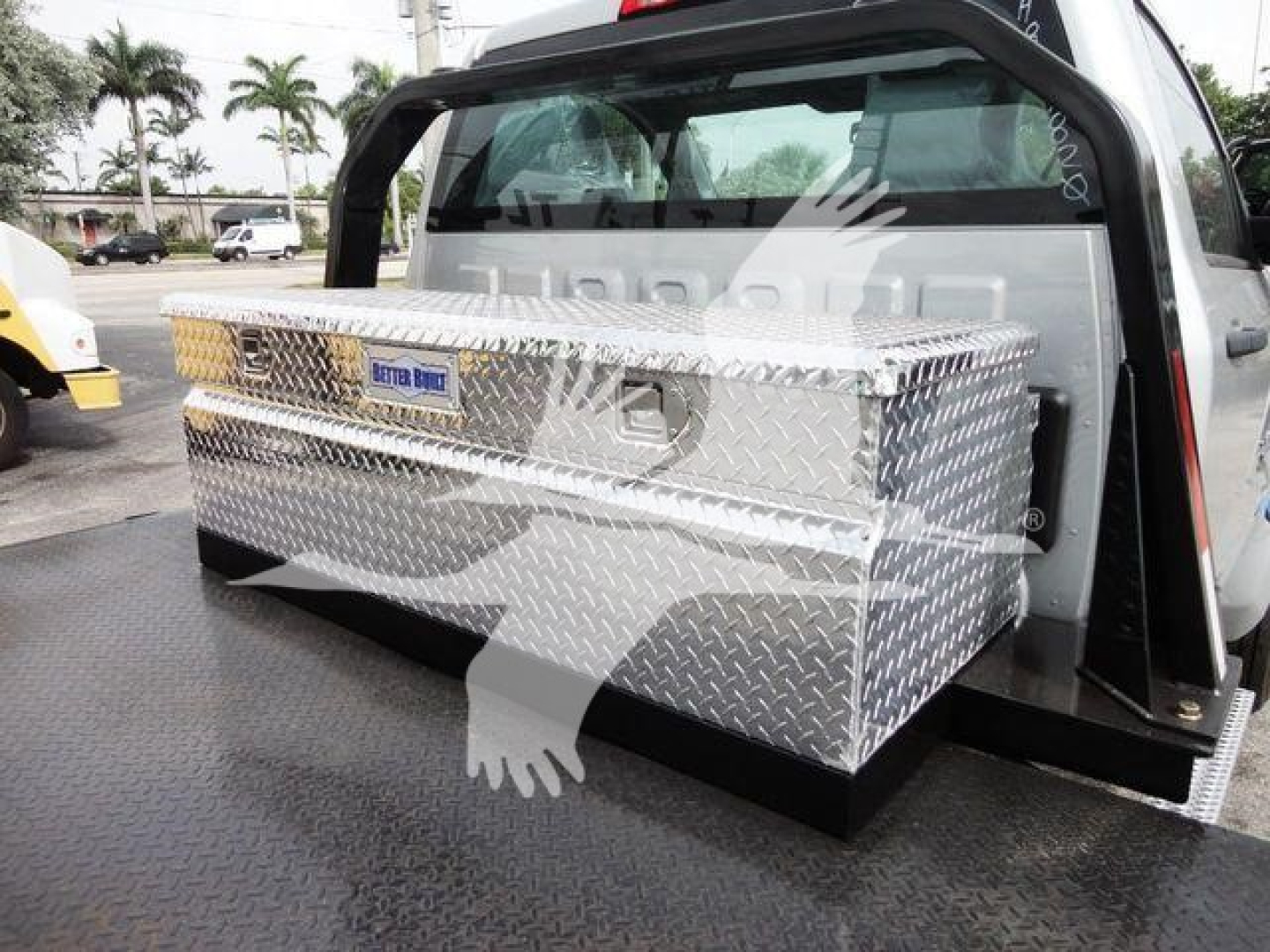 Truck bed toolbox mounted at rear of Silverado 6500HD with diamond-plate aluminum toolbox and rear window. Some branding plate visible.