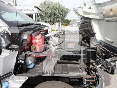 Chevrolet Silverado 6500HD flatbed truck engine bay view with hydraulic components and battery visible.