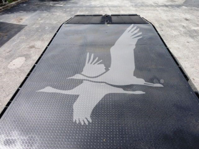 Flatbed truck deck with a large white logo of two birds in flight and textured diamond plate surface.