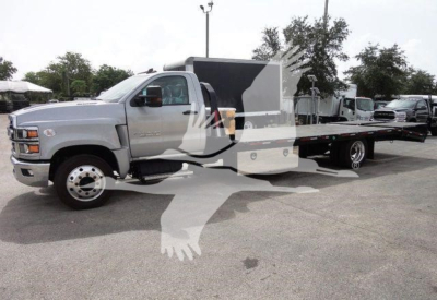 Flatbed tow truck body on a Chevrolet Silverado 6500HD chassis showing long wheelbase and dual rear wheels