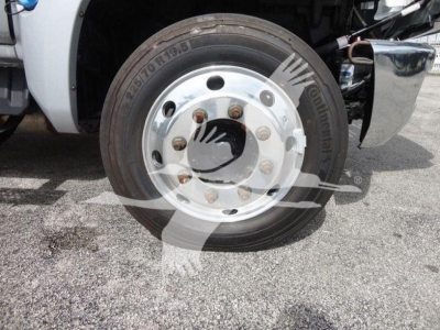 Front wheel of 2023 Chevrolet Silverado 6500HD flatbed truck showing tire with Goodyear? brand text, aluminum wheel, lug nuts, and part of the front fender.
