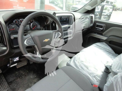 Chevrolet Silverado 6500HD interior cabin showing steering wheel with Chevrolet emblem, dashboard, and front seats wrapped in protective plastic.