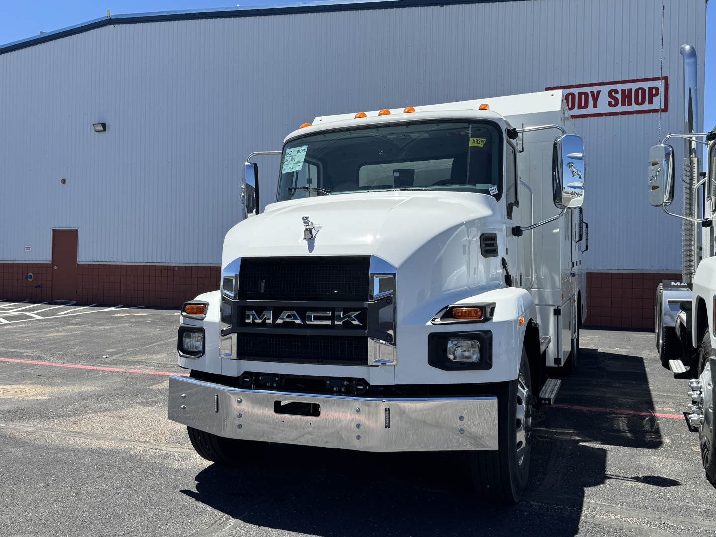 2025 Mack MD7 truck in white with chrome bumper and black grille, front view in dealership lot.