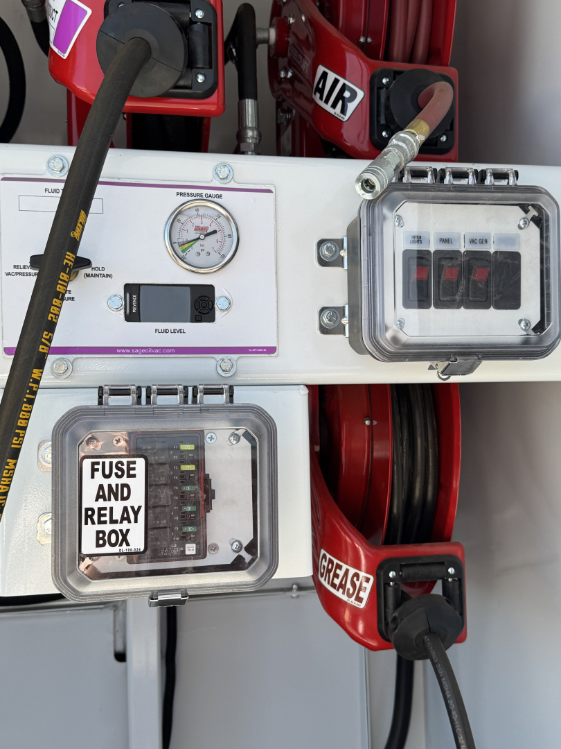 Mack MD7 service truck rear panel showing fuse and relay box, gauge panel, control switches, hoses, and labels.