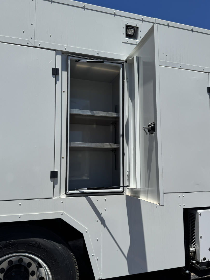 MD7 service truck exterior with an open storage compartment showing empty shelves and interior lighting.