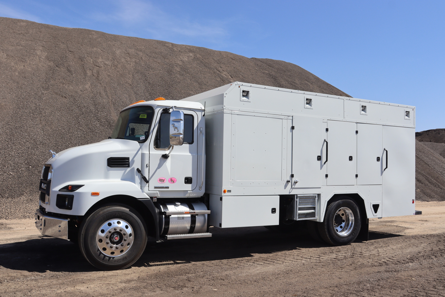 Mack MD7 service truck with utility upfit showing multiple storage compartments and a cab-over-engine design.